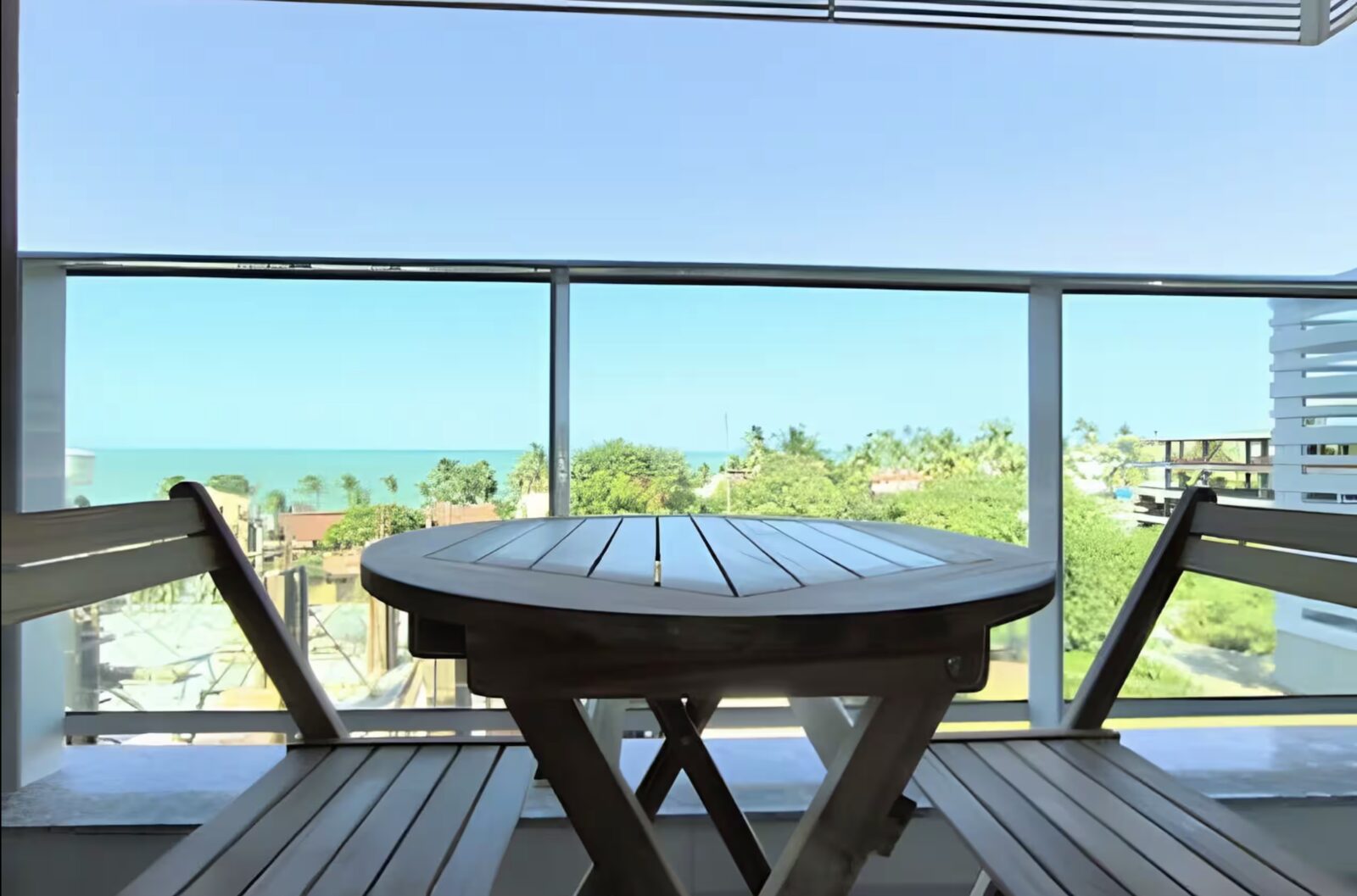 Balcón con mesa y vista al mar de PuraVida Praia